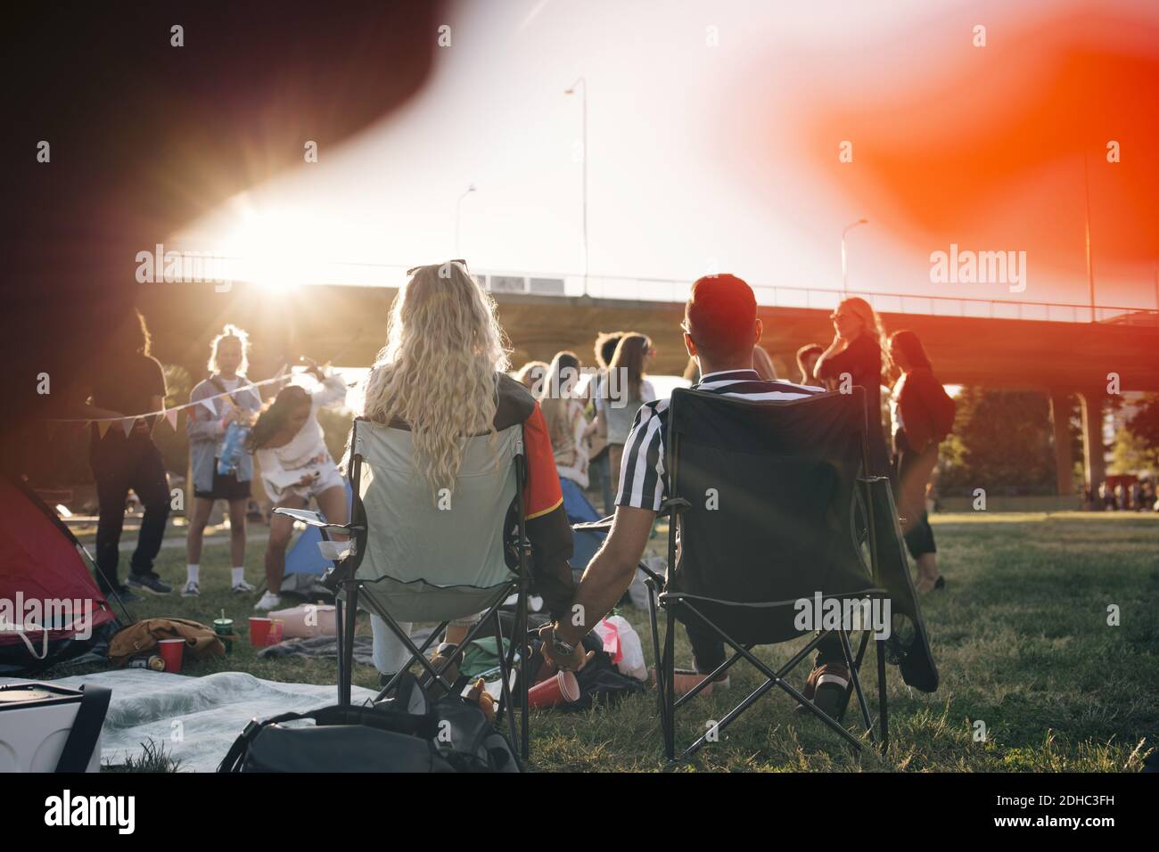 Vue arrière de l'homme et de la femme qui tiennent les mains pendant qu'ils sont assis sur les chaises en festival de musique Banque D'Images