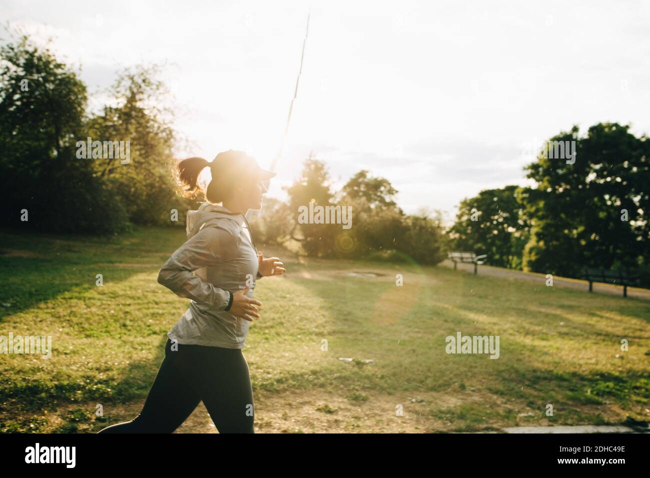 Vue latérale de l'athlète féminine qui fait du jogging au parc sous le soleil jour Banque D'Images
