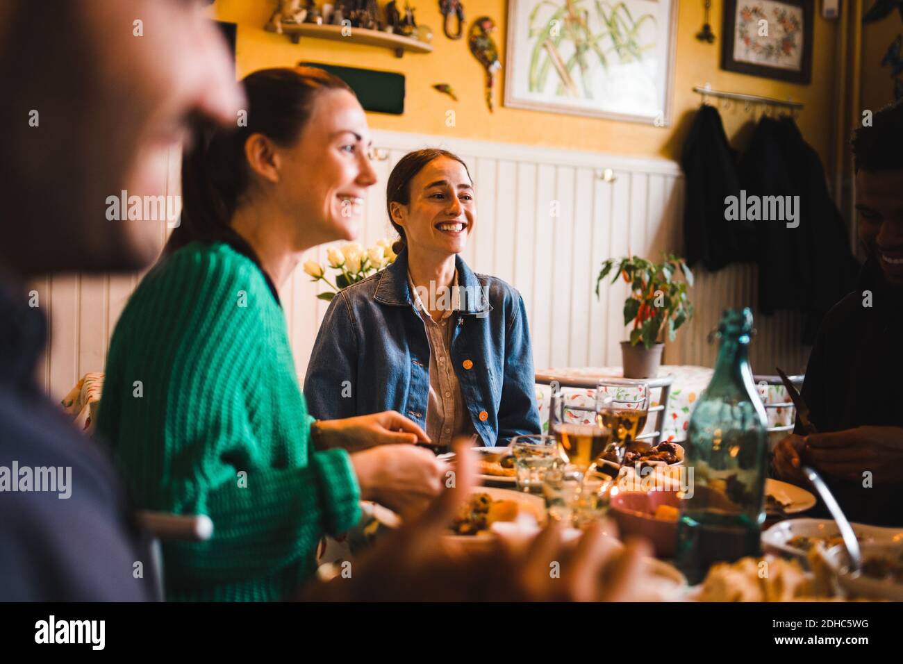 Jeunes femmes souriantes assises à table dans le restaurant tout en appréciant dîner Banque D'Images