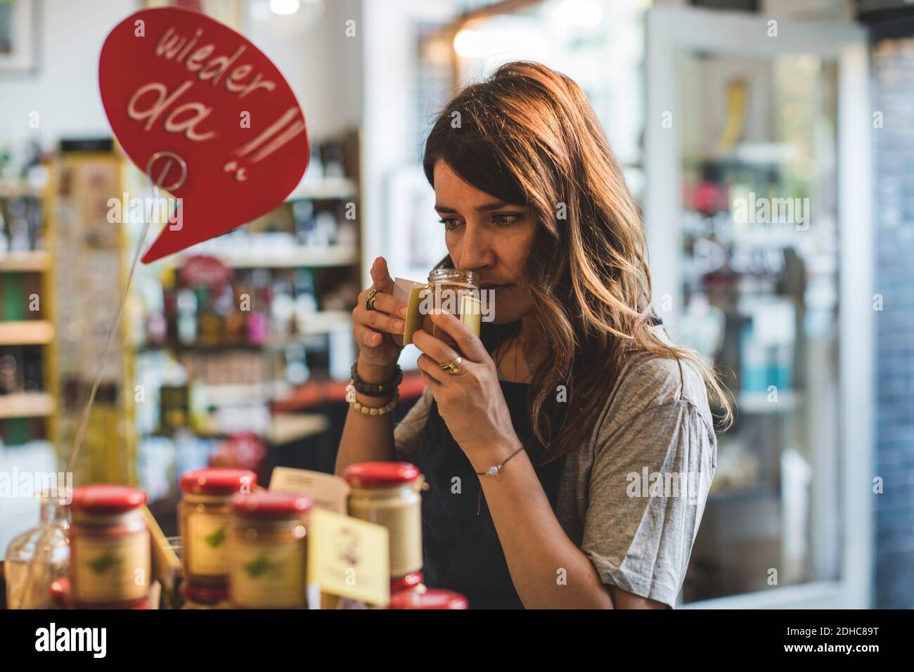 Une femme sentait la nourriture dans un pot au comptoir déli Banque D'Images