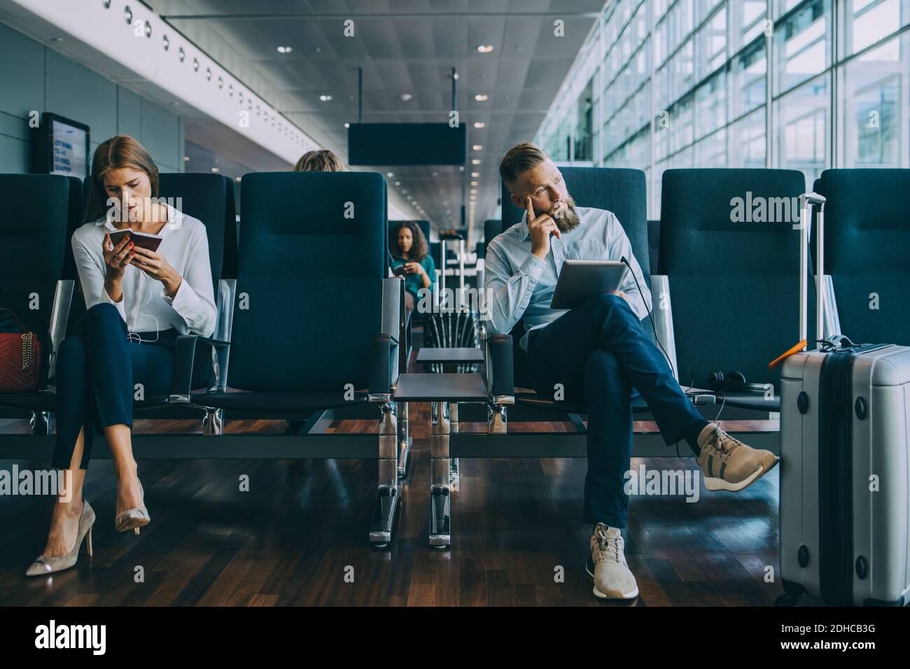 Homme d'affaires attentionné, assis près d'une collègue de salle d'attente de l'aéroport Banque D'Images