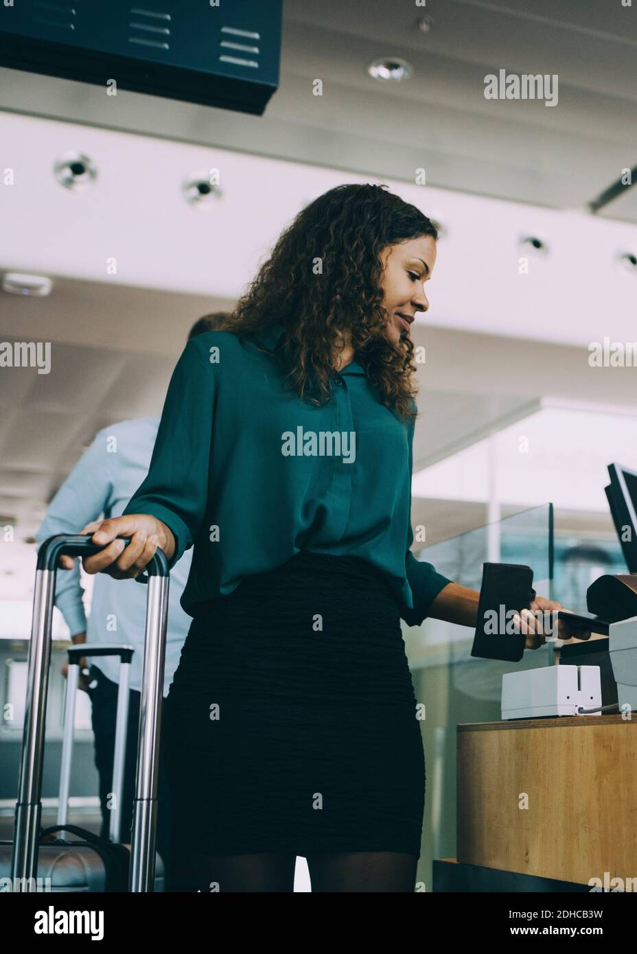 Femme d'affaires qui balaie un smartphone au comptoir d'enregistrement de l'aéroport Banque D'Images