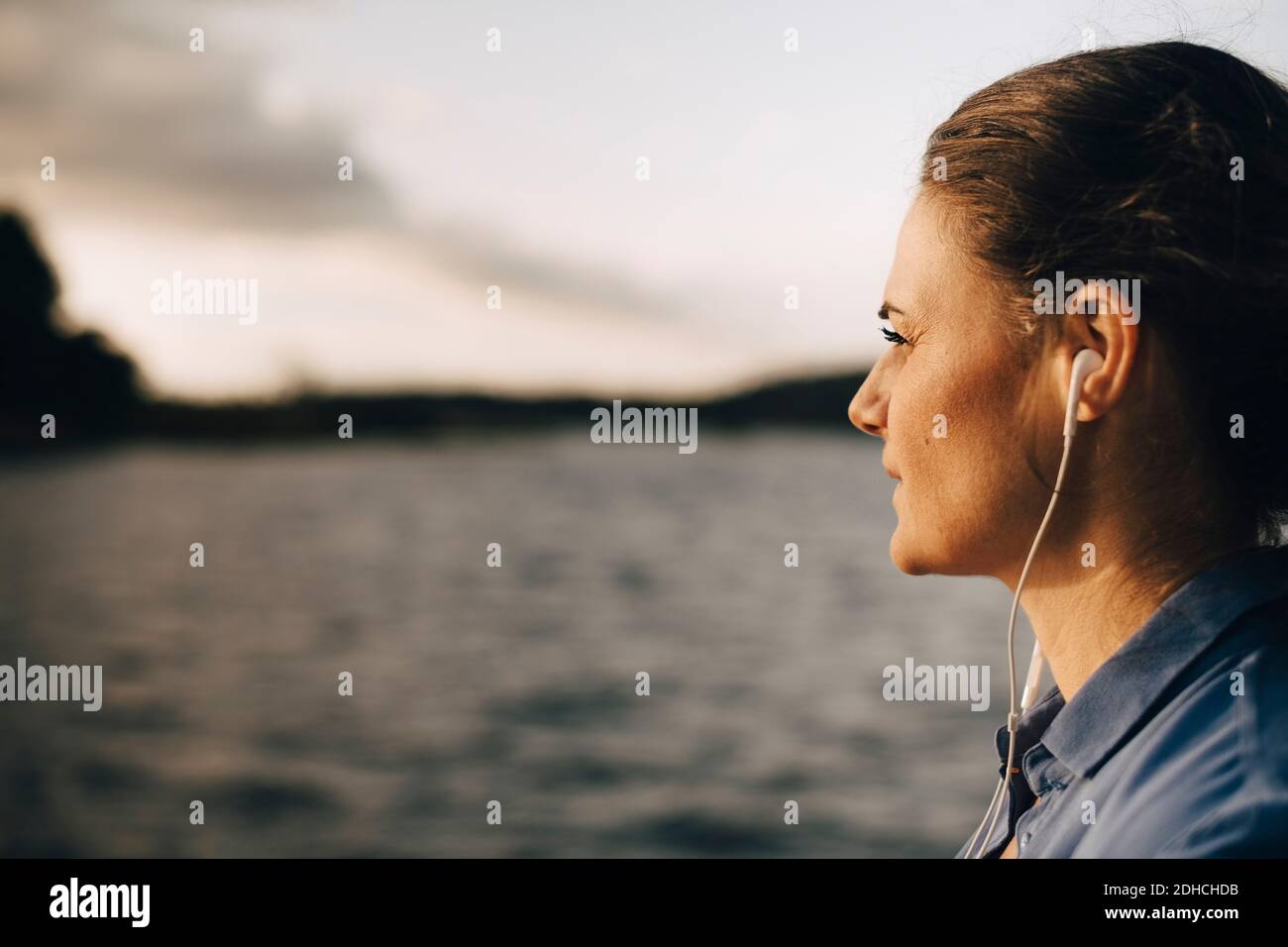 Gros plan sur une femme attentionnés qui écoute de la musique à travers des écouteurs au bord du lac en vacances d'été Banque D'Images