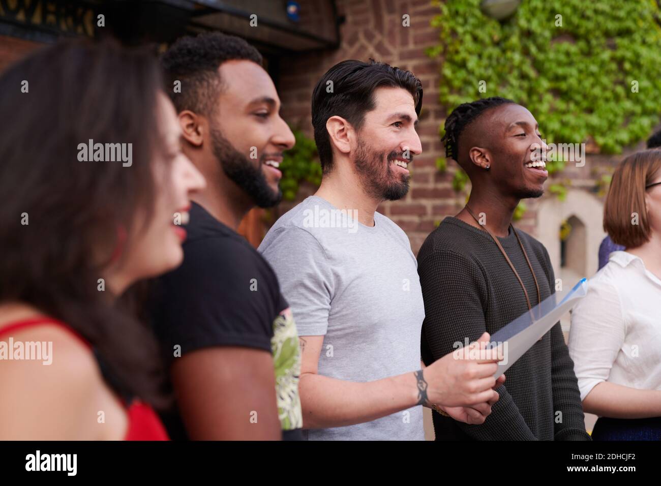 Chœur de chanteurs avec partitions de musique chantant à l'extérieur de l'école de langue Banque D'Images Chœur de chanteurs avec partitions de musique chantant à l'extérieur de l'école de langue Banque D'Images
