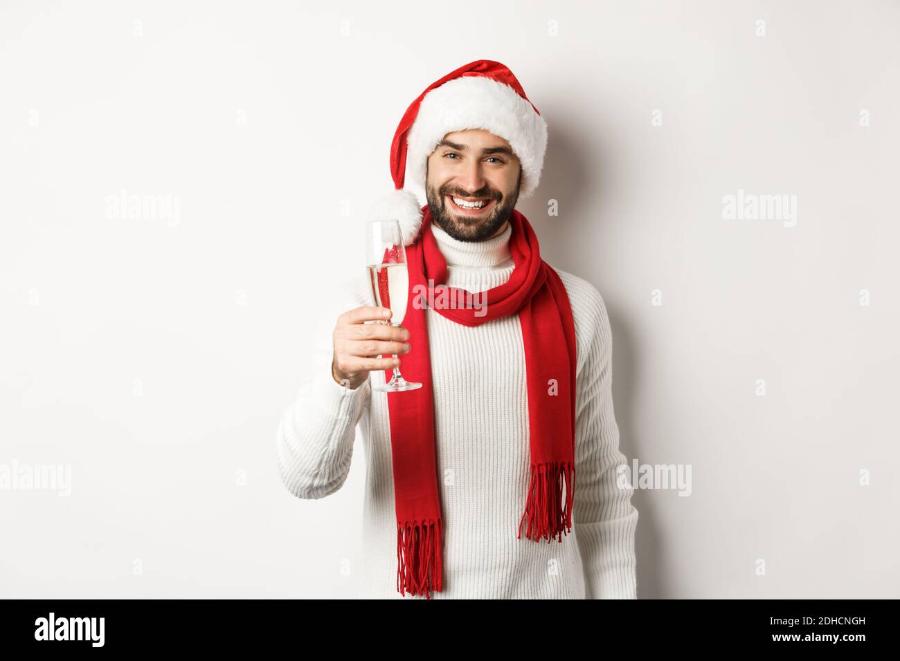Concept de fête de Noël et de vacances. Beau jeune homme avec barbe, faire un toast le jour de l'an, tenant un verre de champagne Banque D'Images
