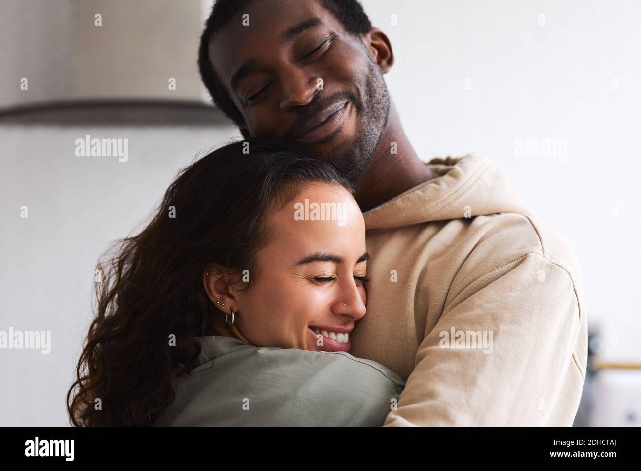 Un jeune couple d'ethnie mixte affectueux se couchant en cuisine ensemble Banque D'Images