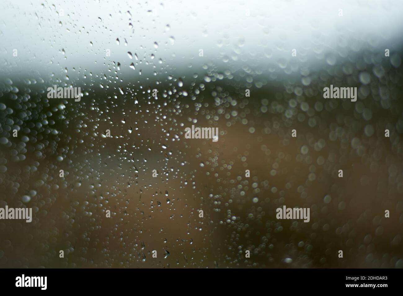 Le verre d'un véhicule couvert de gouttes de pluie au coucher du soleil un jour d'automne Banque D'Images