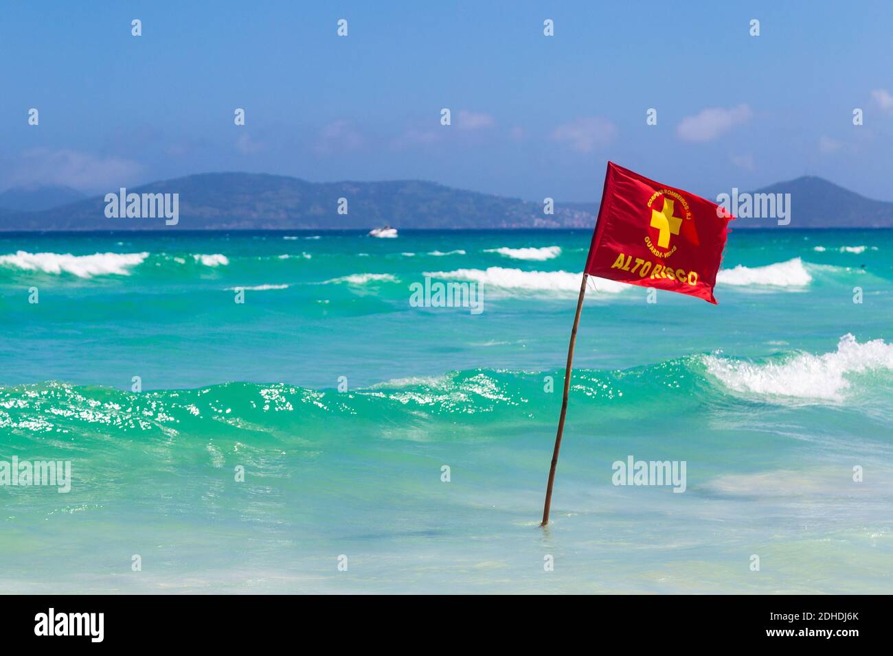 Signe d'avertissement d'un drapeau rouge sur une belle plage avec un ciel bleu et une mer turquoise. Do forte Beach à Cabo Frio, Rio de Janeiro, Brésil. Banque D'Images