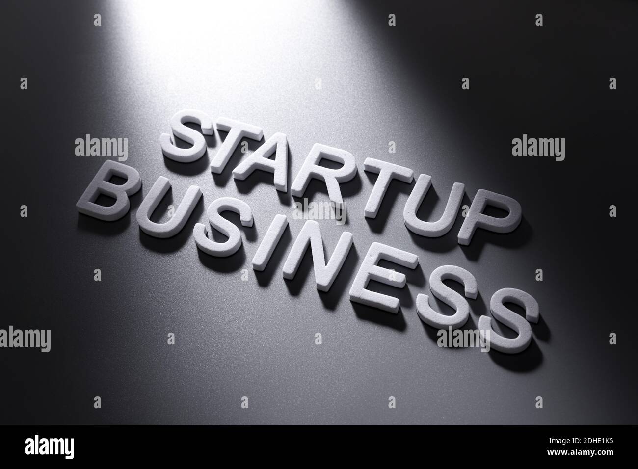 Une inscription motivante « Startup Business » écrite avec des lettres en plastique blanc et s'allument sur fond gris foncé Banque D'Images