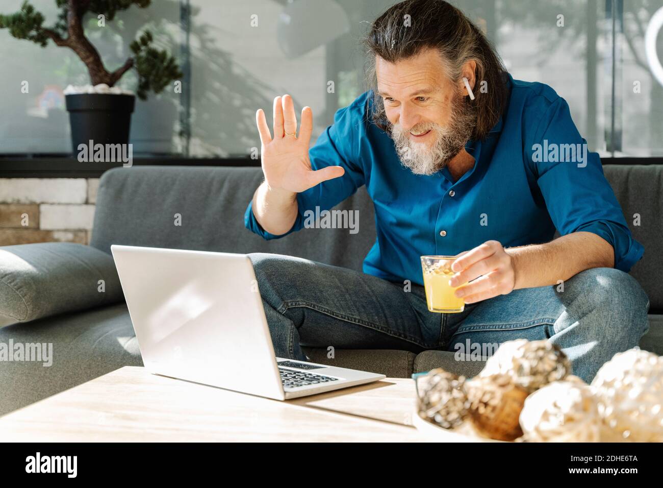 Homme mûr avec une barbe qui boit du jus d'orange et regarde à son lapto  Photo Stock - Alamy