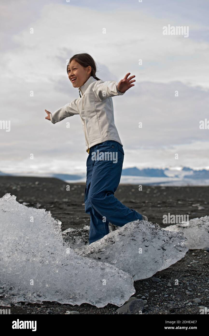 Fille qui se balance sur l'iceberg bloqué au lagon du glacier en Islande Banque D'Images