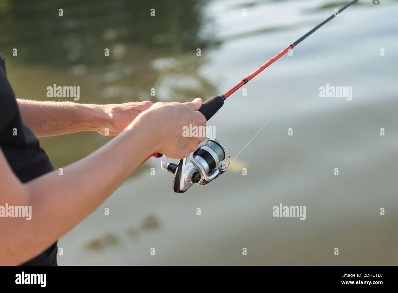 Les mains des pêcheurs pêchent dans l'eau lors d'une journée ensoleillée d'été. Banque D'Images