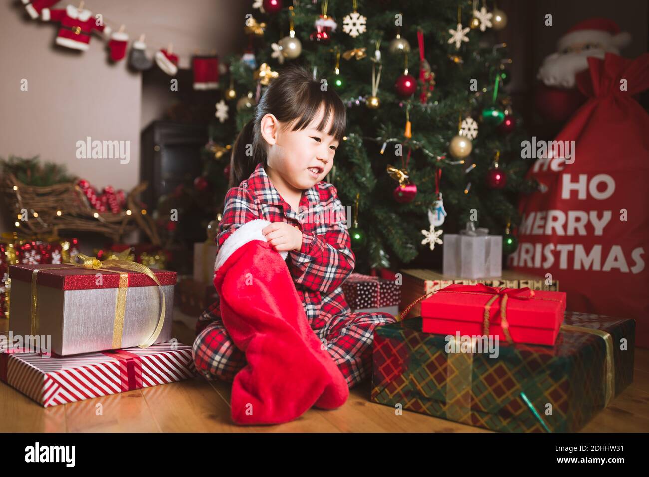 une jeune fille s'assoit sur le sol et cherche un cadeau de grande chaussette Banque D'Images