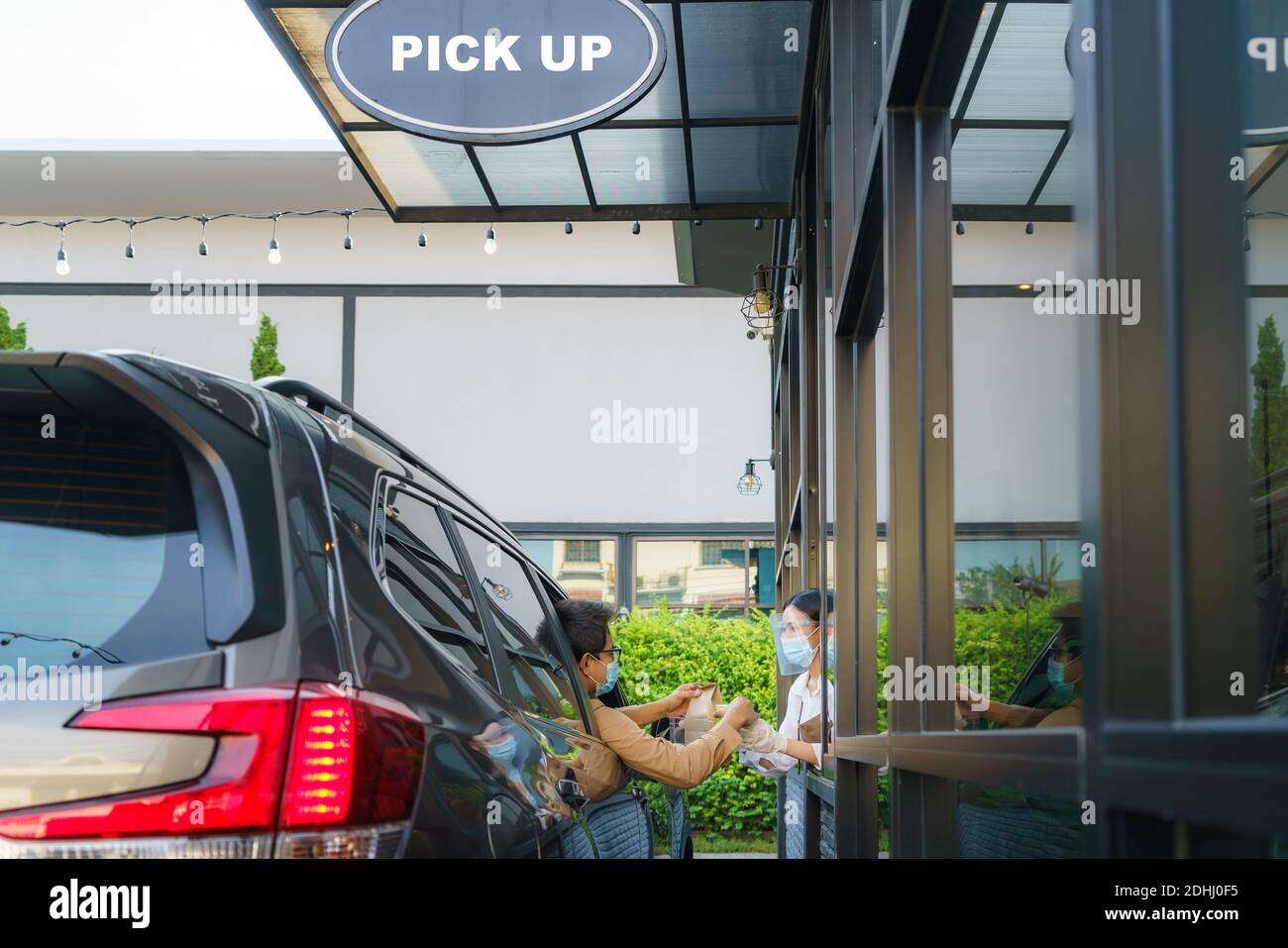 Homme asiatique en masque de protection prenant sac de nourriture et café avec une serveuse portant un masque facial et un masque facial à passage en voiture pendant l'outbrea du coronavirus Banque D'Images