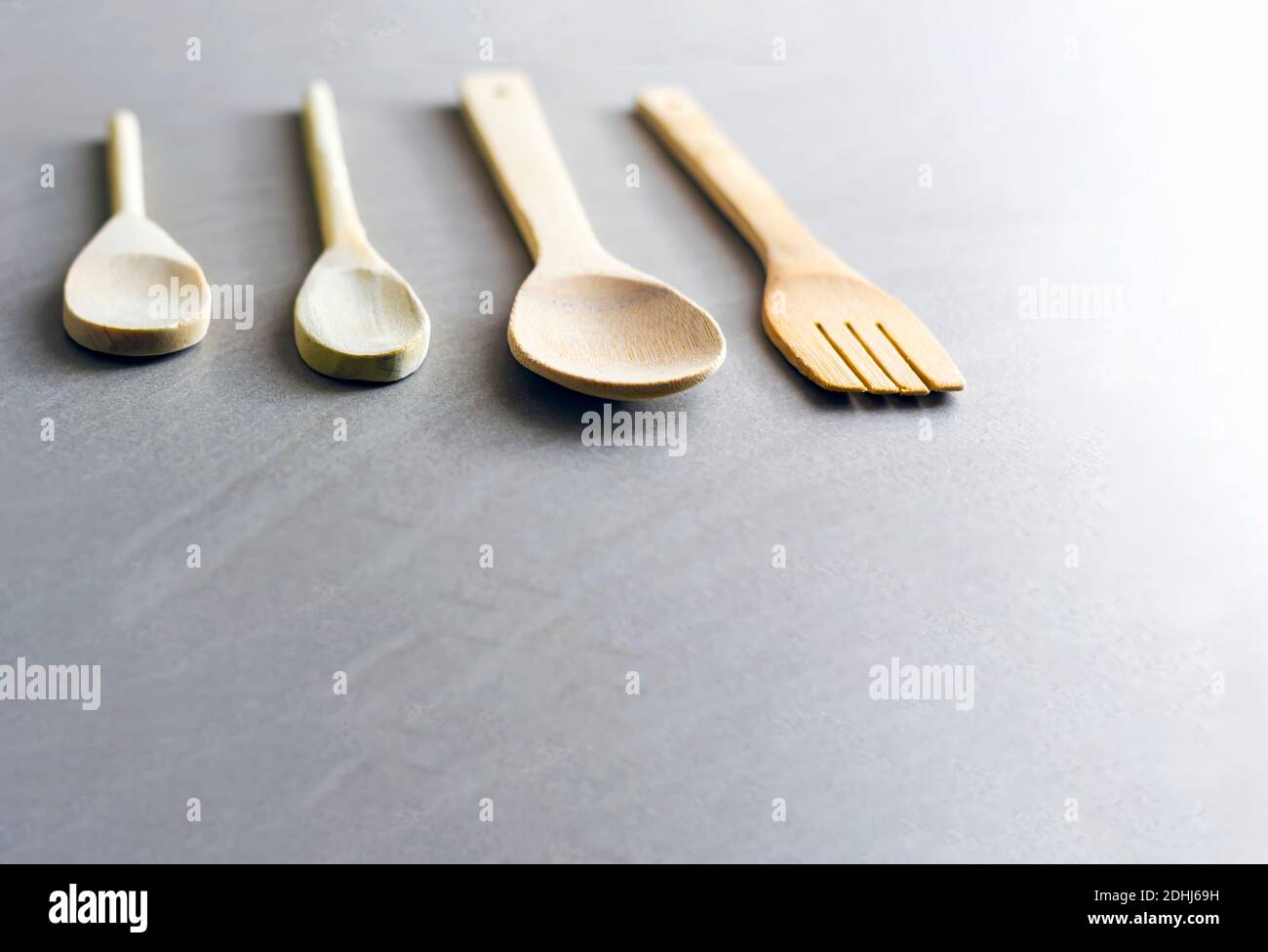 Ensemble d'ustensiles de cuisine en bois disposés sur une table en marbre gris. Accent sélectif sur la fourche à sculpter. Banque D'Images