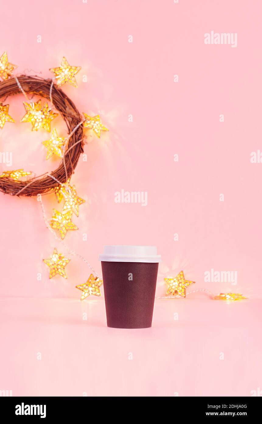 Maquette de tasse en papier à café noir avec lumières dorées de noël dans une couronne sur fond rose, modèle pour la publicité, le design, le café, le restaurant, Banque D'Images Maquette de tasse en papier à café noir avec lumières dorées de noël dans une couronne sur fond rose, modèle pour la publicité, le design, le café, le restaurant, Banque D'Images