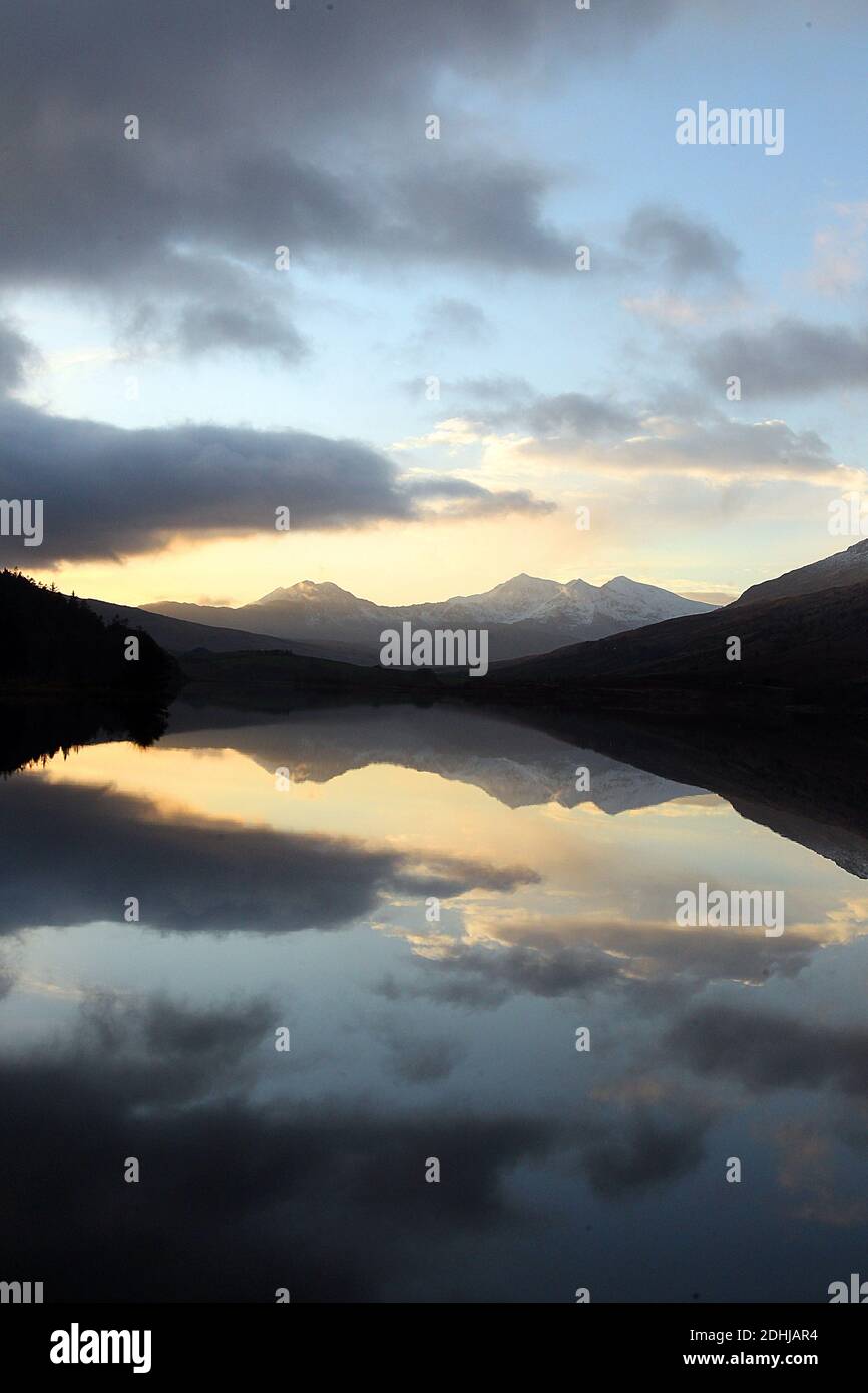 Coucher de soleil sur le Snowdon Horseshoe en travers montrant la neige récente au-delà d'un calme plat Llynnau Mymbyr. Pays de Galles. Photo prise le 5 décembre 2020 Banque D'Images