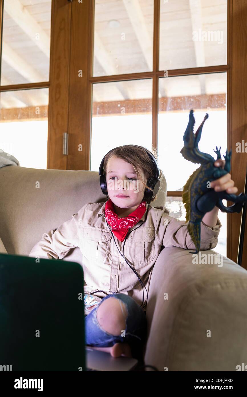 jeune garçon portant une tenue safari et un casque pour regarder un film sur ordinateur portable Banque D'Images