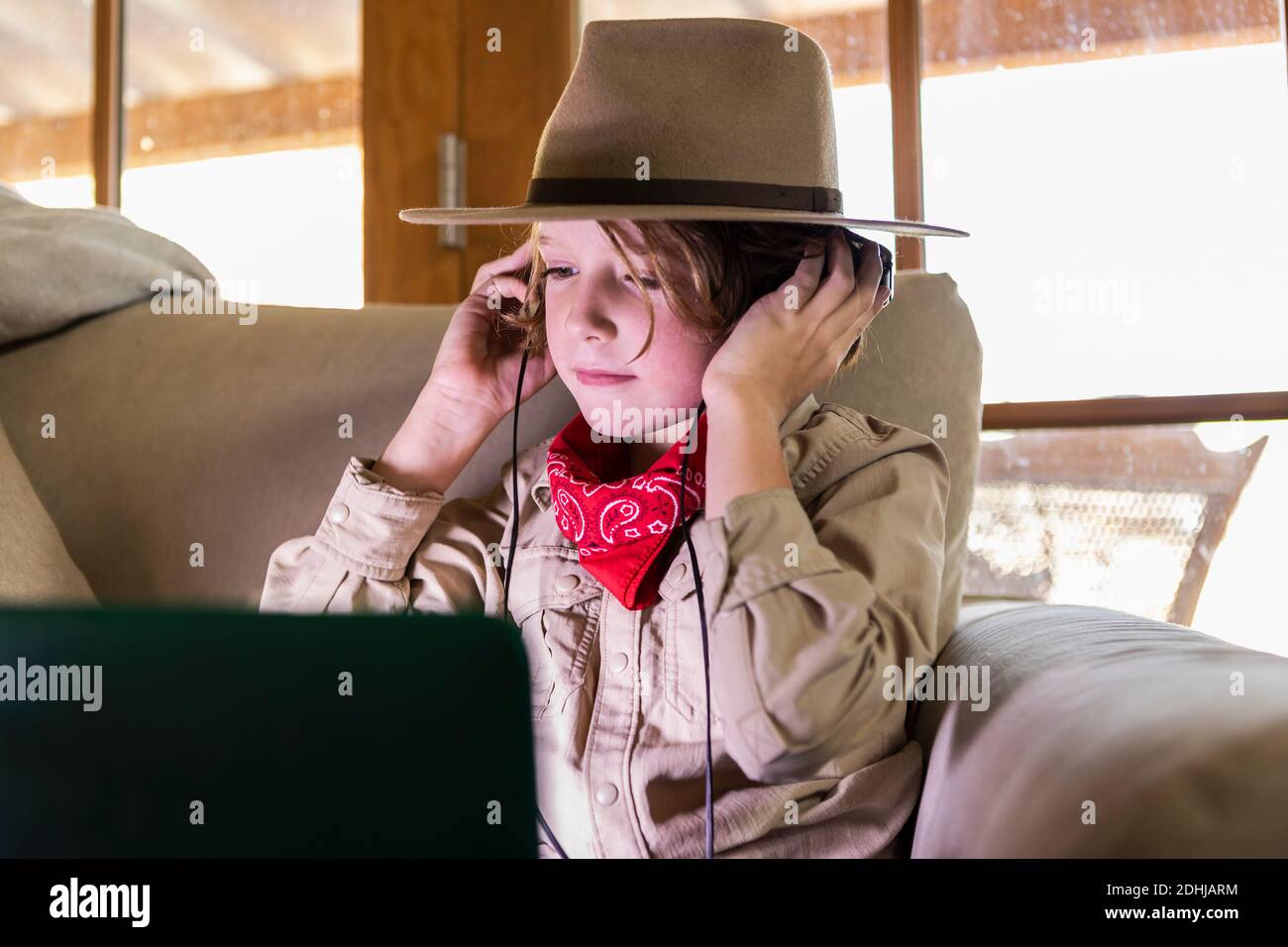 jeune garçon portant une tenue safari et un casque pour regarder un film sur ordinateur portable Banque D'Images