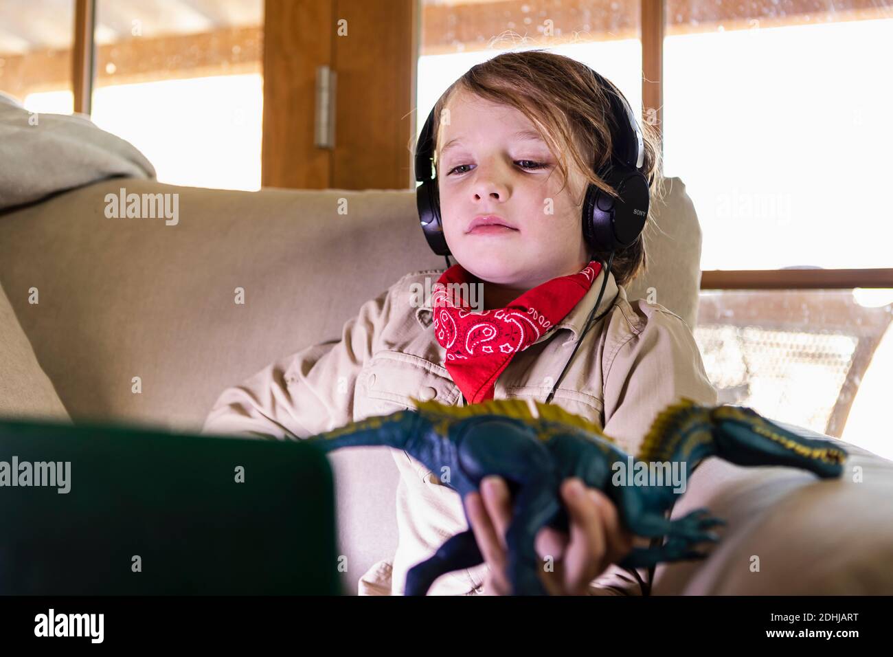 jeune garçon portant une tenue safari et un casque pour regarder un film sur ordinateur portable Banque D'Images