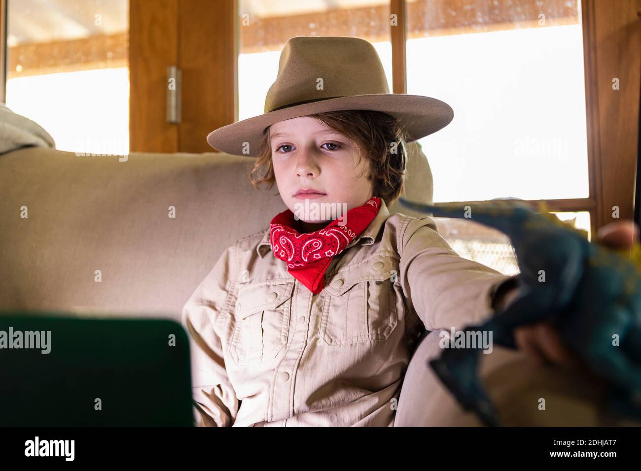 jeune garçon portant une tenue safari et un casque pour regarder un film sur ordinateur portable Banque D'Images
