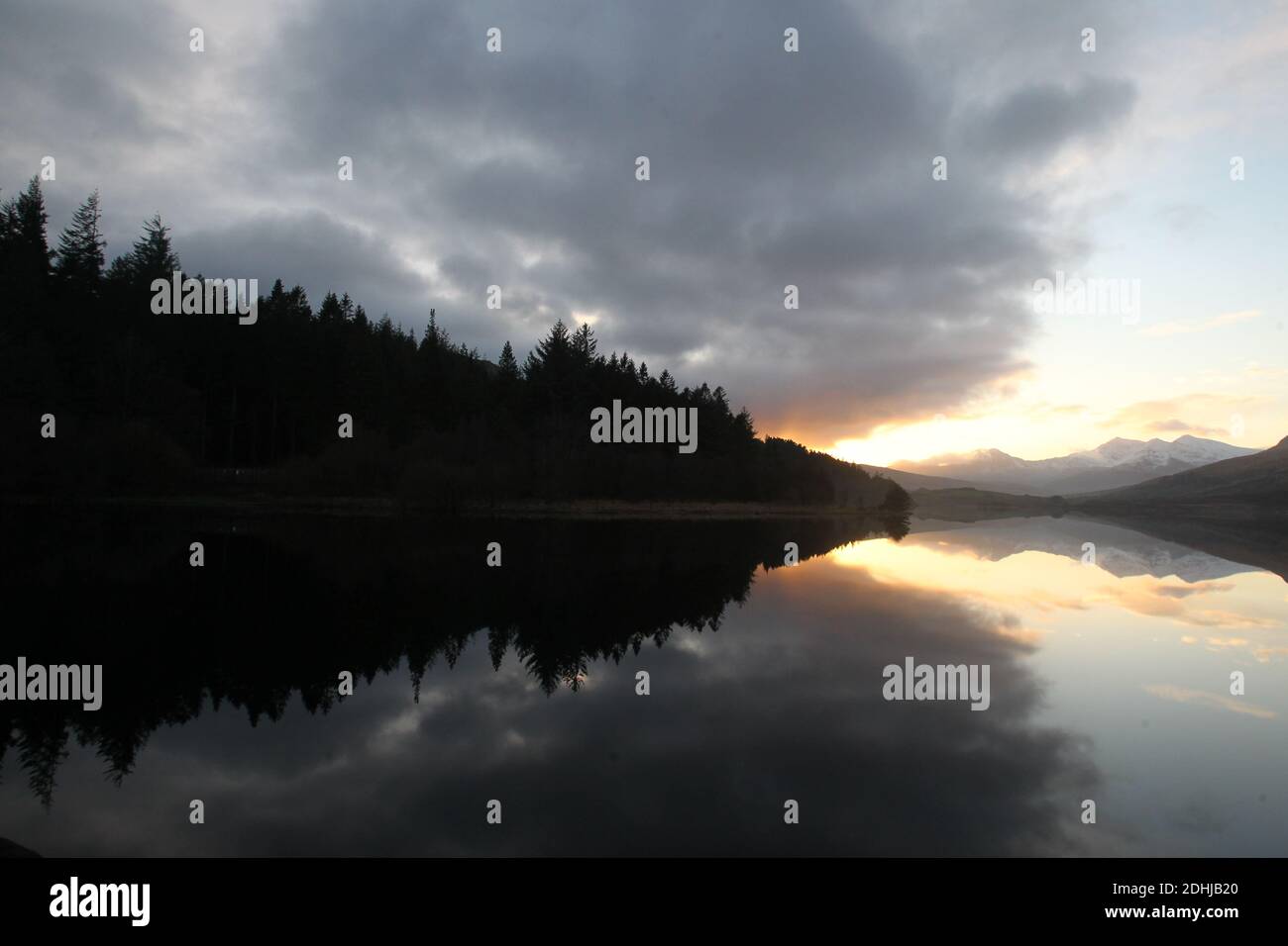 Coucher de soleil sur le Snowdon Horseshoe en travers montrant la neige récente au-delà d'un calme plat Llynnau Mymbyr. Pays de Galles. Photo prise le 5 décembre 2020 Banque D'Images