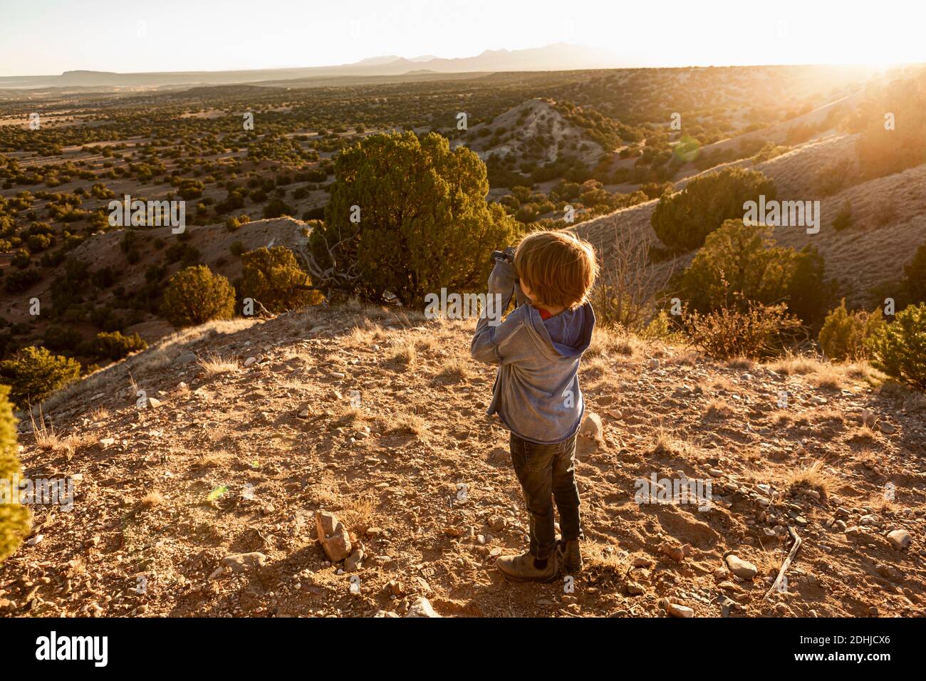 Jeune garçon dans le bassin de Galisteo regardant à travers des jumelles au coucher du soleil Banque D'Images