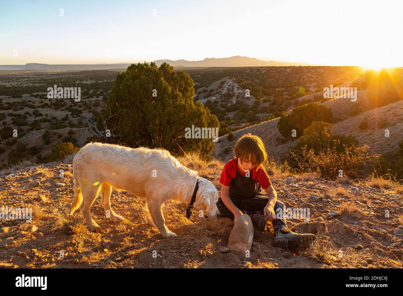 Jeune garçon à Galisteo Basin au coucher du soleil avec son anglais Crème Golden Retreiver Banque D'Images