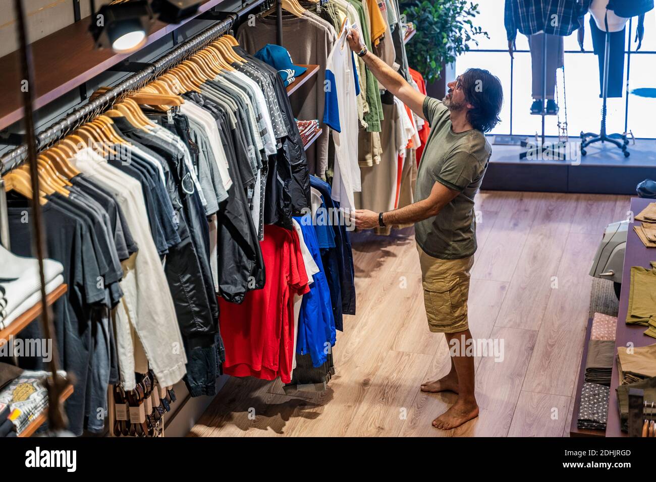 De la vue ci-dessus homme client choisissant des t-shirts dans un vêtement stocker Banque D'Images De la vue ci-dessus homme client choisissant des t-shirts dans un vêtement stocker Banque D'Images