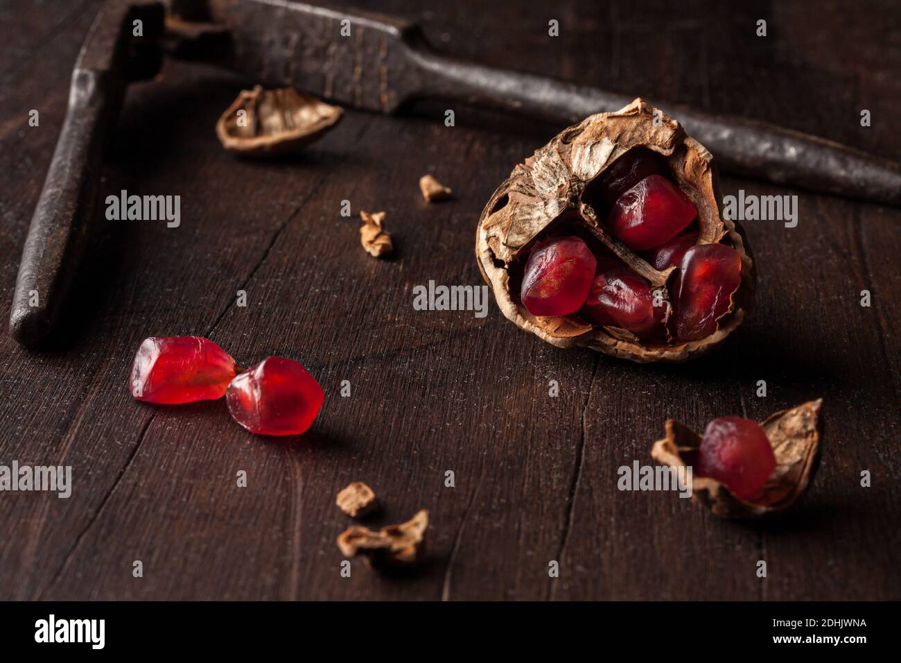 Composition à vie fixe avec graines de grenade rouges mûres disposées en coques en noyer sur fond en bois sombre Banque D'Images