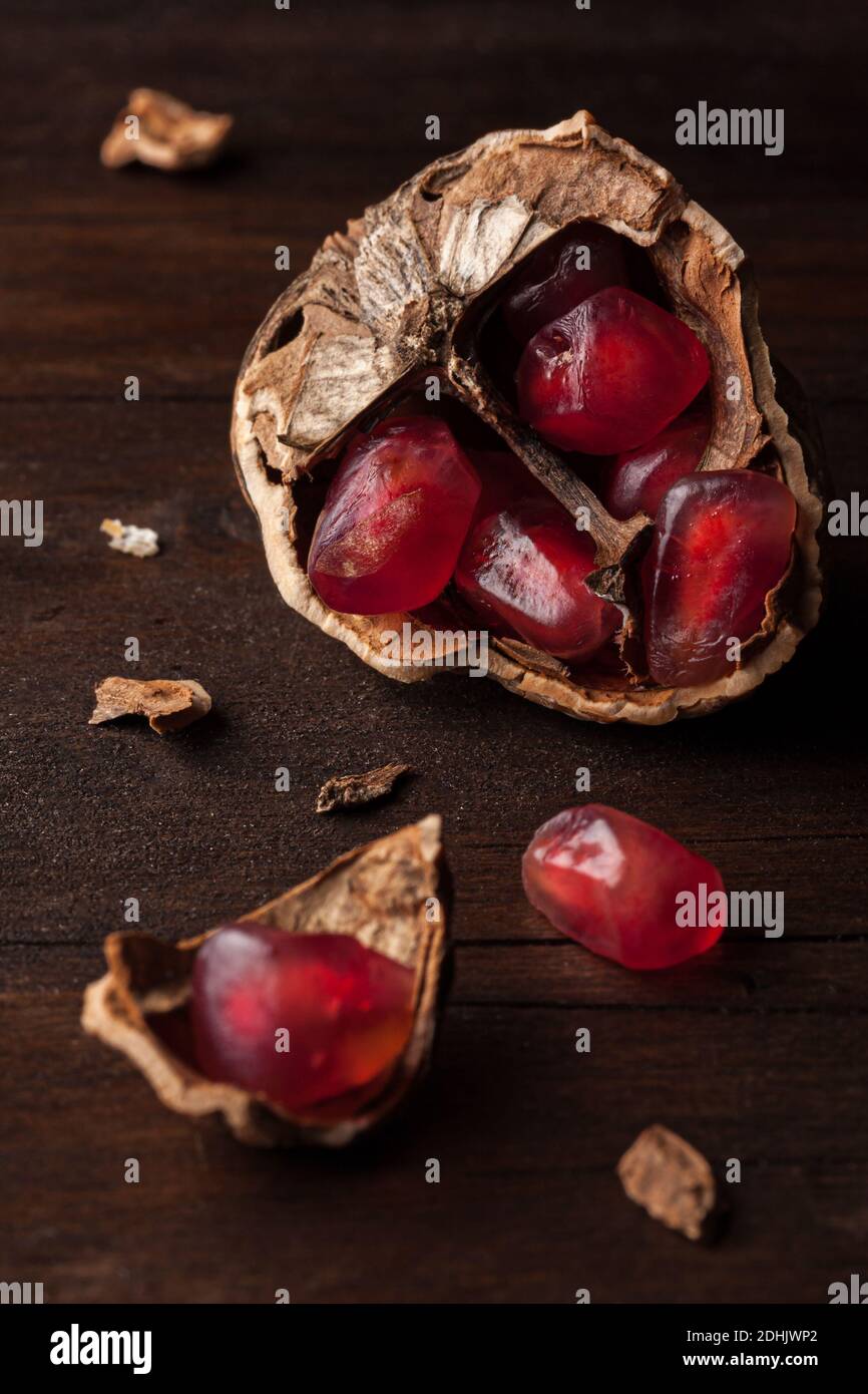Vue du dessus composition de vie fixe avec graines de grenade rouges mûres disposés dans des coques en noyer sur fond de bois sombre Banque D'Images