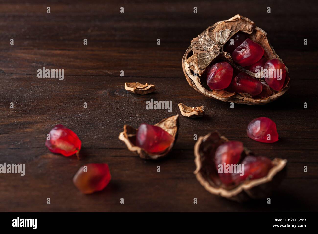 Vue du dessus composition de vie fixe avec graines de grenade rouges mûres disposés dans des coques en noyer sur fond de bois sombre Banque D'Images