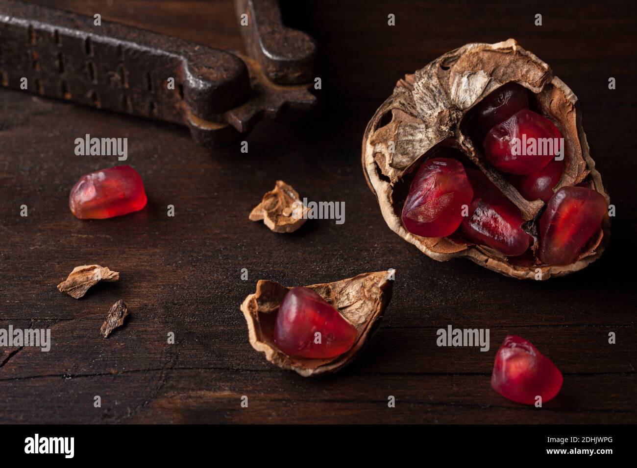 Vue du dessus composition de vie fixe avec graines de grenade rouges mûres disposés dans des coques en noyer sur fond de bois sombre Banque D'Images