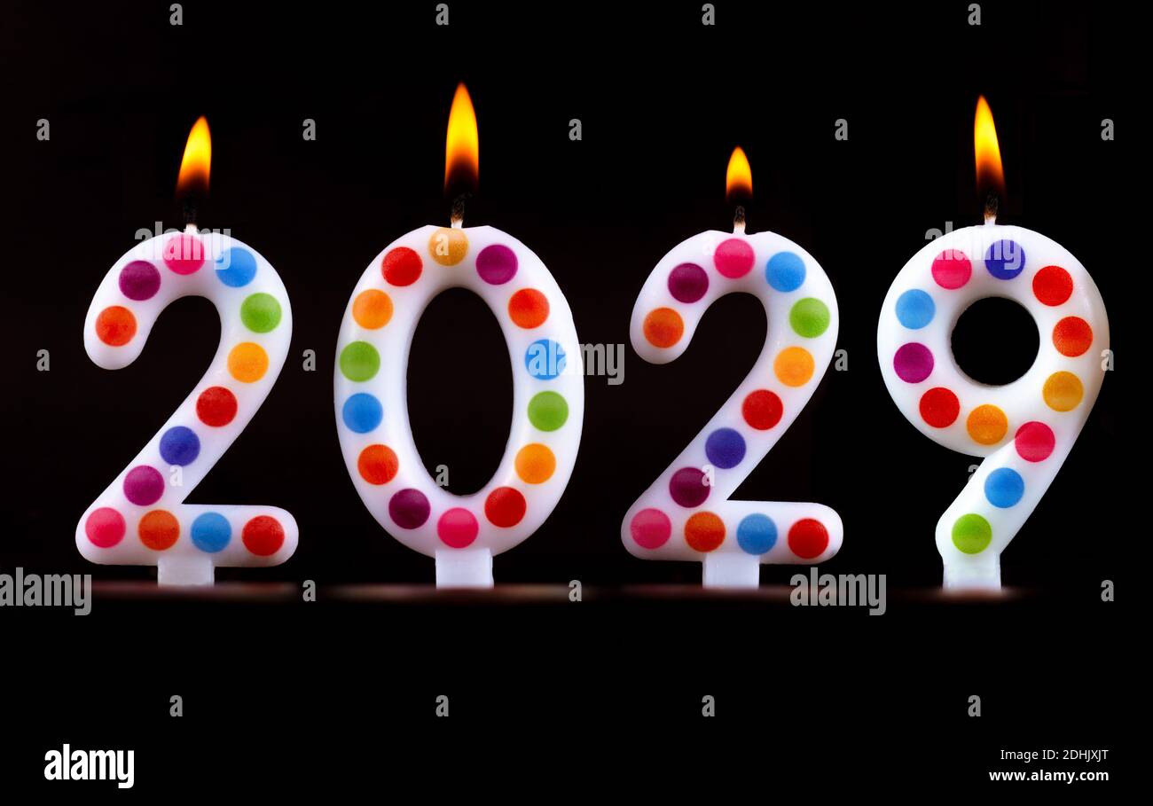 Quatre bougies de couleur écrire des nombres de flamme bonne année 2029 arrière-plan noir Banque D'Images