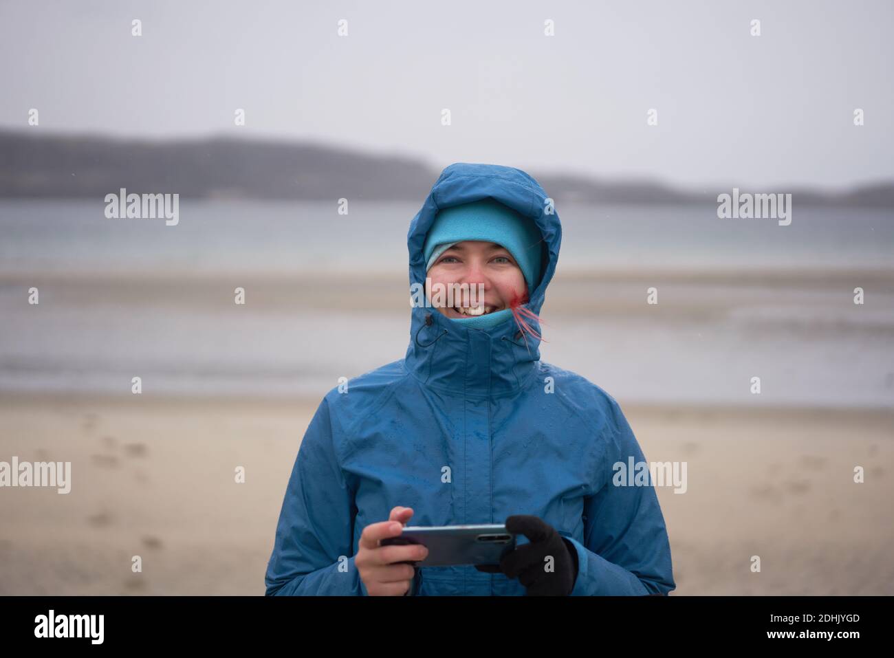 Une femme exploratrice ravie dans une veste imperméable et chaude avec un  téléphone portable en bord de mer par temps venteux et en regardant la  caméra Photo Stock - Alamy