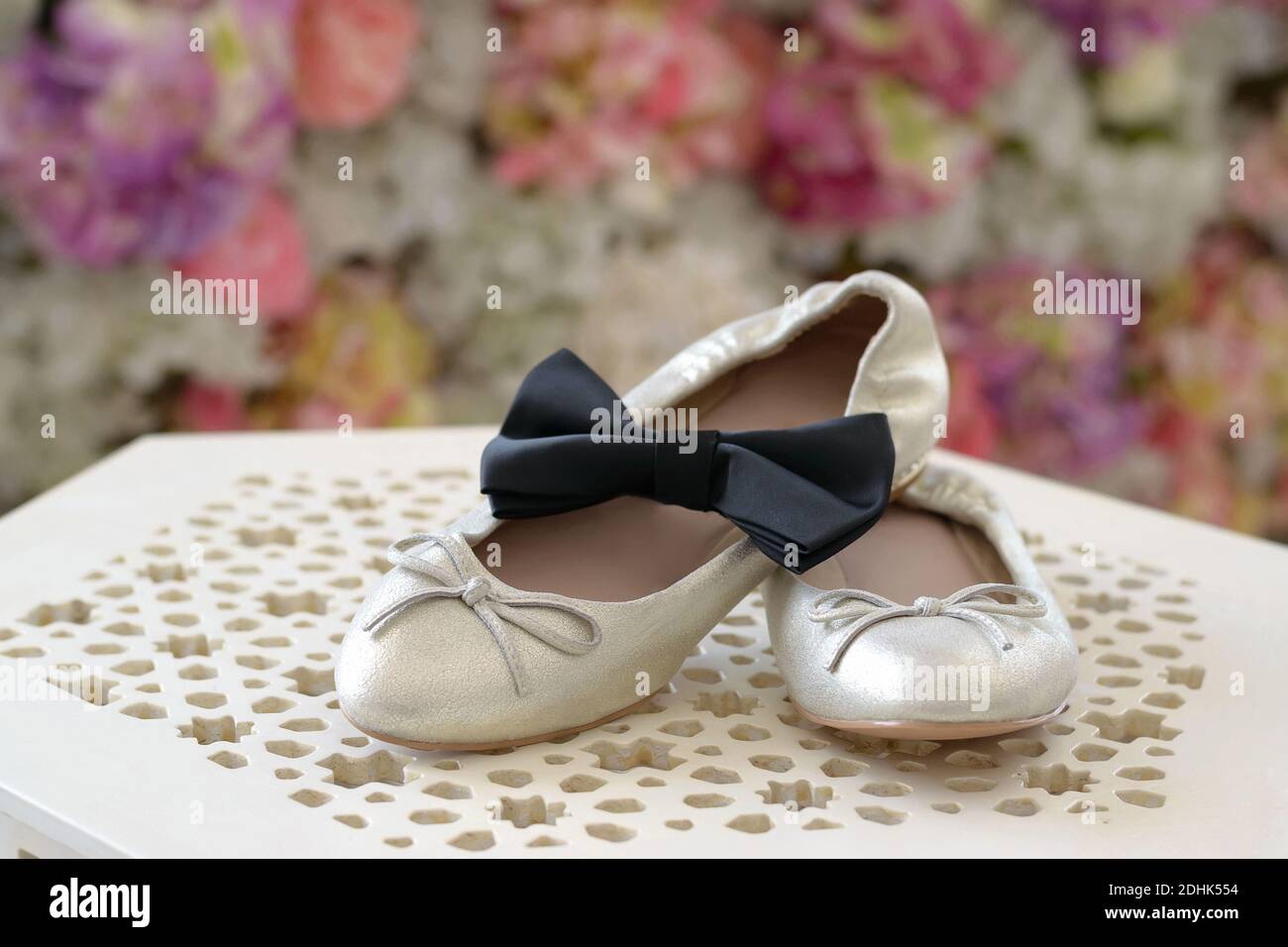 Les chaussures de mariage de la mariée et le noeud papillon de la mariée se tiennent sur une table de nuit magnifique, sur un fond de fleurs. Accessoires de mariage Banque D'Images