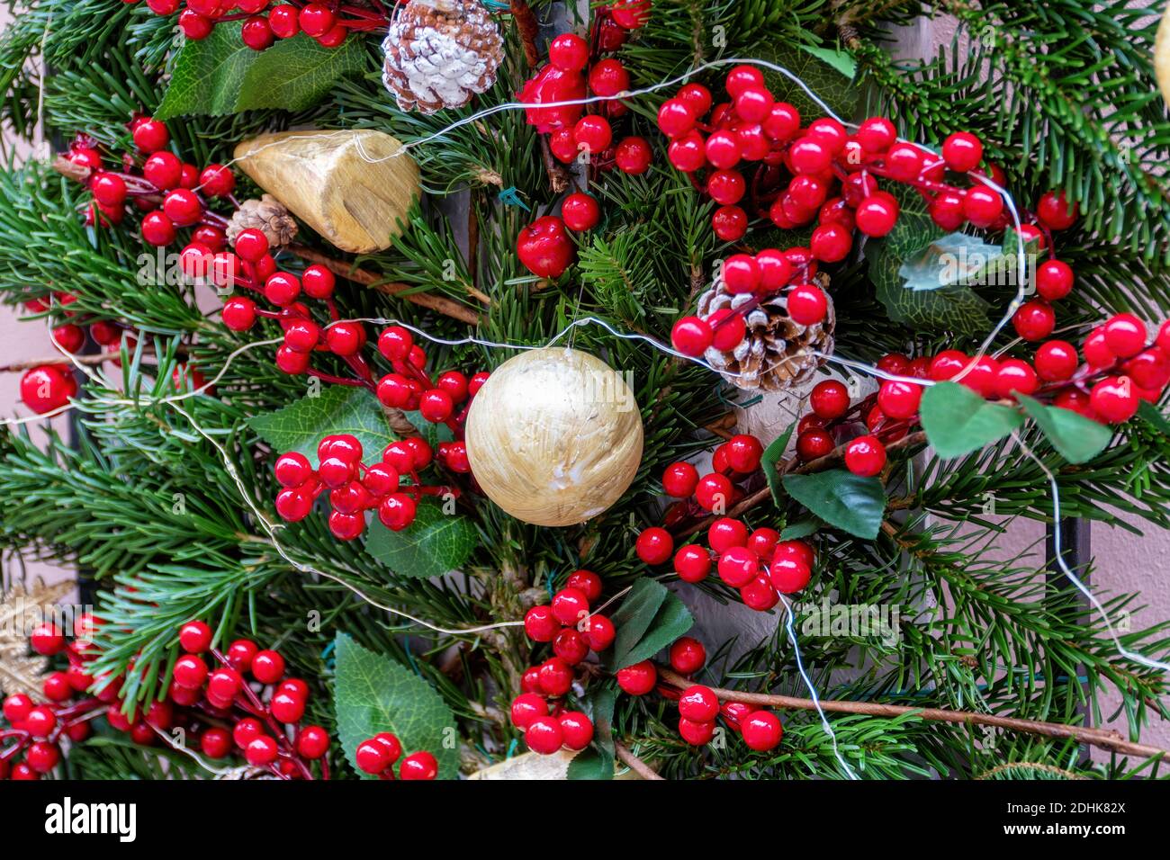 Une boule d'or, avec des cônes de pin, des branches de pin, un balai de boucher et des lumières, utilisés comme décorations de Noël. Concentration centrale. Banque D'Images