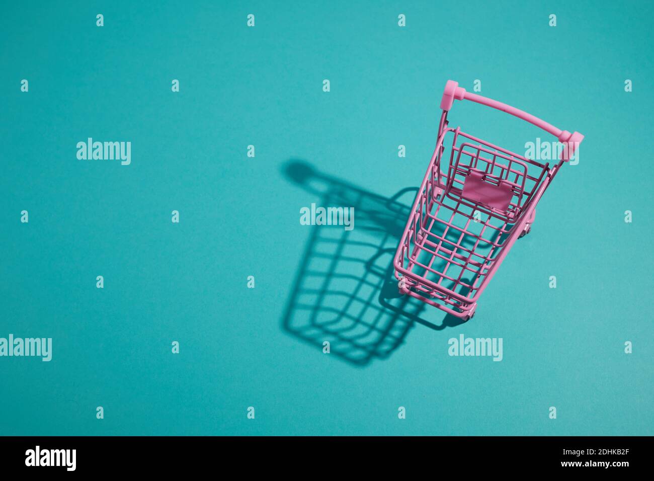 Chariot à chariots rose sur fond couleur aqua. Banque D'Images