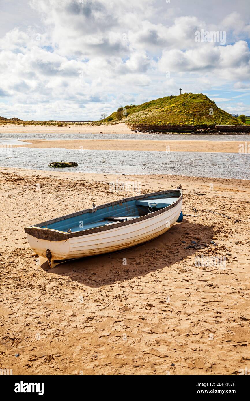 Un petit bateau de pêche ouvert sur la plage à marée basse avec Church Hill en arrière-plan, à Alnmouth, Northumberland, Royaume-Uni Banque D'Images
