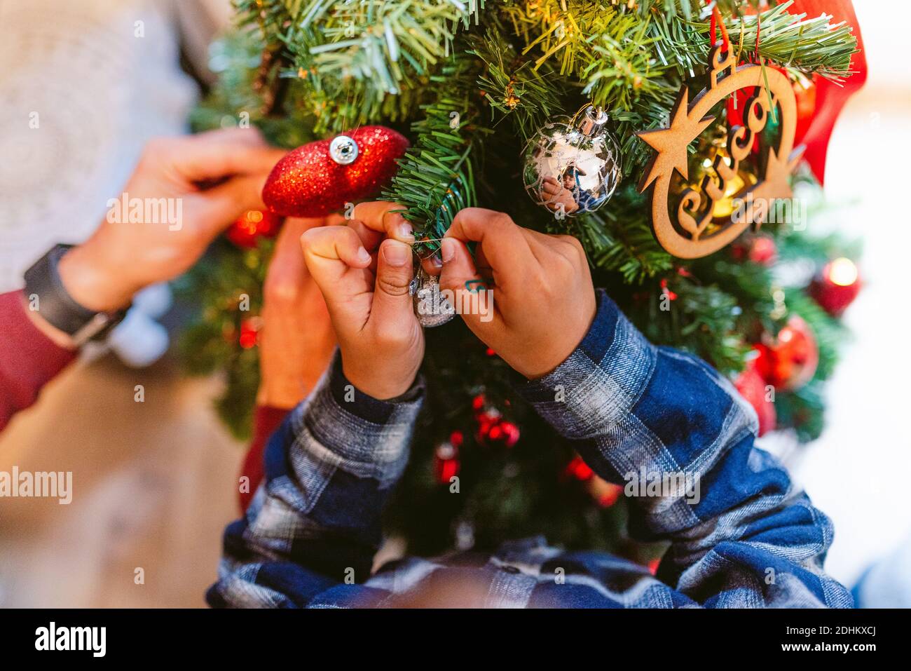 les petites mains mignonnes décorent l'arbre de noël à la maison pendant la saison des vacances. l'enfance noël à la maison. en hiver avec des sodes naturels chauds Banque D'Images