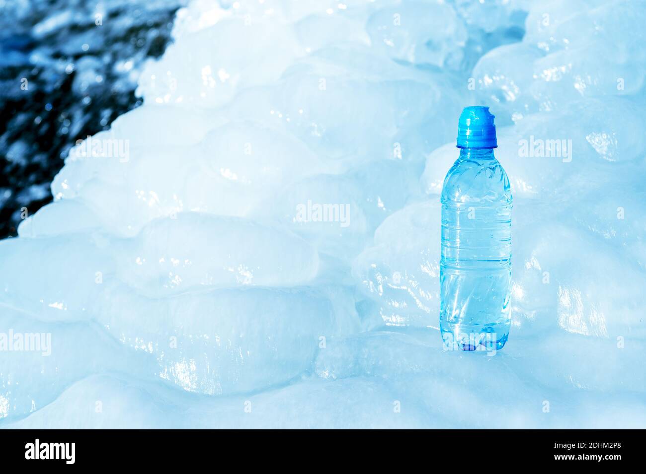 Bouteille en plastique bleu sur glace sur fond de l'eau de fonte du  glacier. Arrière-plan. Le concept de pureté naturelle de l'eau Photo Stock  - Alamy