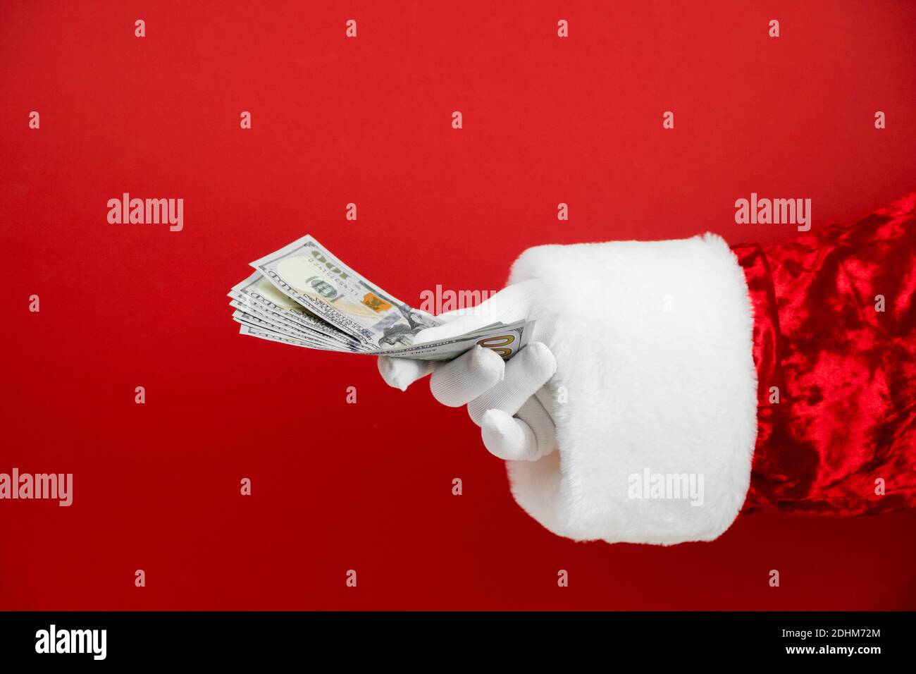Main du Père Noël tenant de l'argent sur fond rouge. Main avec de l'argent. Banque D'Images