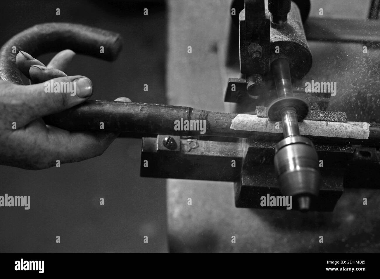 Artisan façonnant des poignées de parapluies en bois à la main dans un atelier traditionnel, Banque D'Images