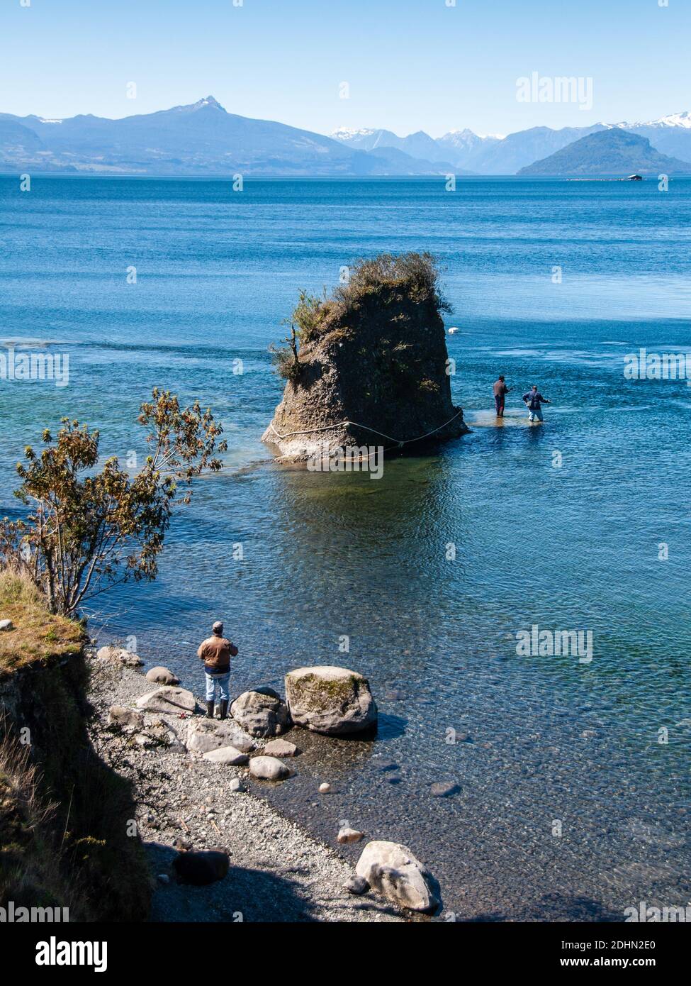 Osorno, Chili - 27 septembre 2009 : deux hommes pêchent dans le lac Lago Rupanco, avec derrière eux les montagnes volcaniques des Andes patagoniennes. Banque D'Images