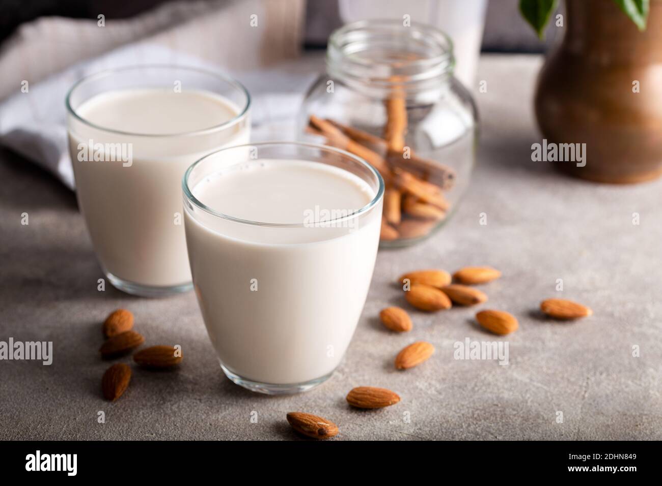 Lait d'amande biologique fait maison dans un verre sur fond de pierre avec bâtons de cannelle. Banque D'Images