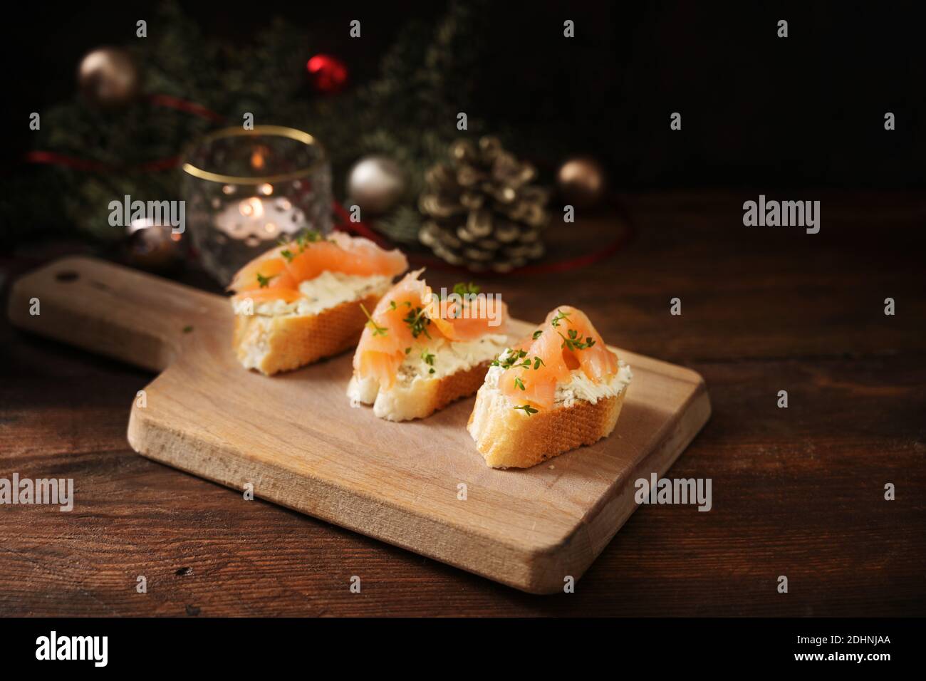 Canapés festifs, pain de baguette à la crème au fromage et saumon sur un  plan de cuisine en bois, table rustique sombre avec décorations de Noël,  espace pour les copies, séle Photo