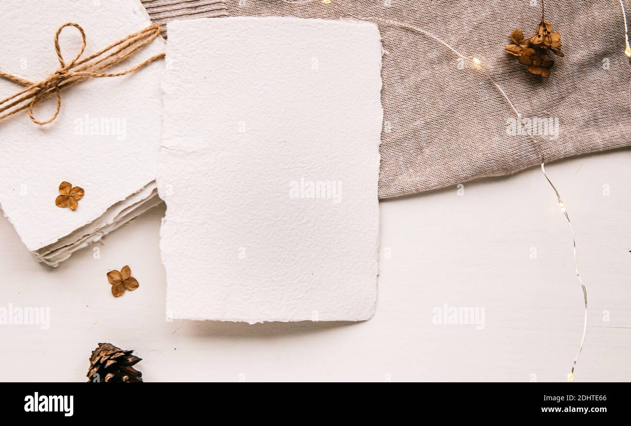Maquette de lettre vierge sur papier artisanal. Enveloppe de lettre, cônes de pin, fil d'artisanat et bougie. Tons pastel, beige, style confortable en hygge. Plat, dessus Banque D'Images