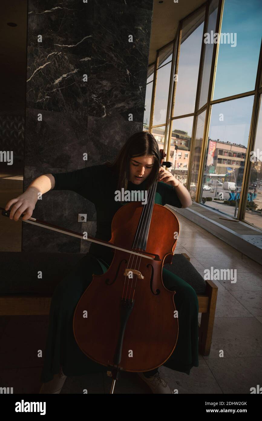 Adolescente avec violoncelle, posant dans un hall. Banque D'Images