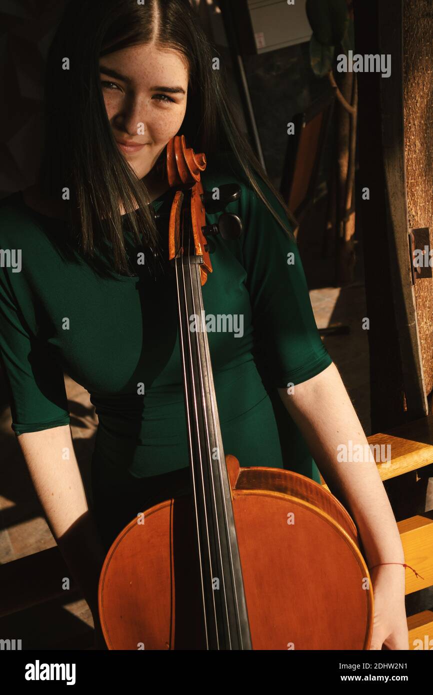 Adolescente avec violoncelle, posant dans un hall. Banque D'Images