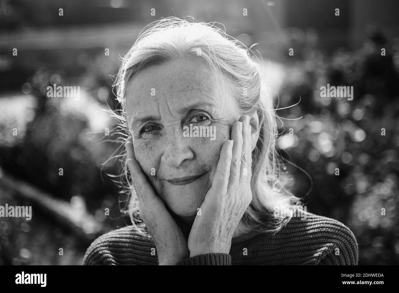 Portrait noir et blanc d'une femme âgée aux cheveux gris et face avec des rides dehors se détendre au parc Banque D'Images